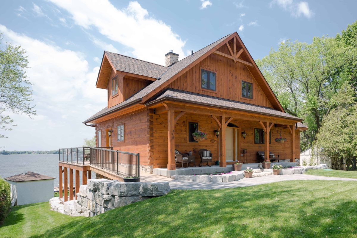 side of log cabin showing wrap around porch above stone foundation