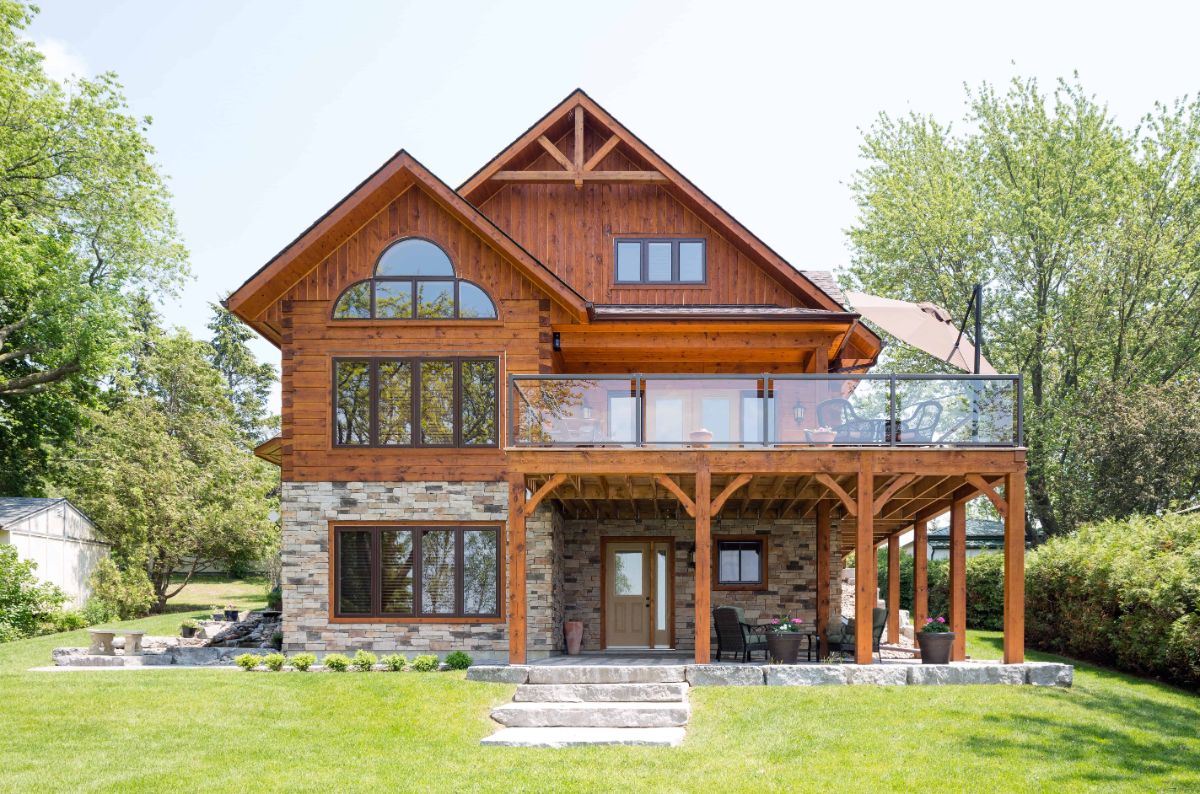 back of log cabin with open deck on top level and stone foundation with walk out basement