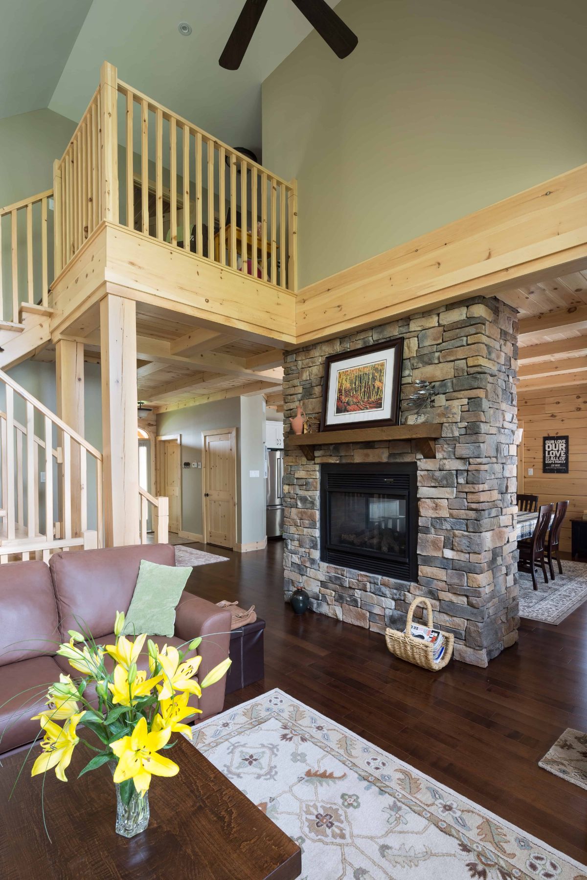 stone fireplace between living and dining room with light wood stairs to second floor on left side of image