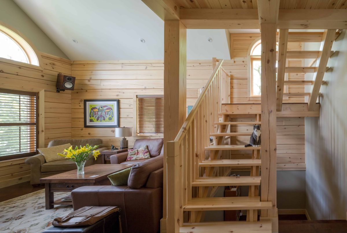 light wood stairs leading to loft with dark brown leather sofa below stairs