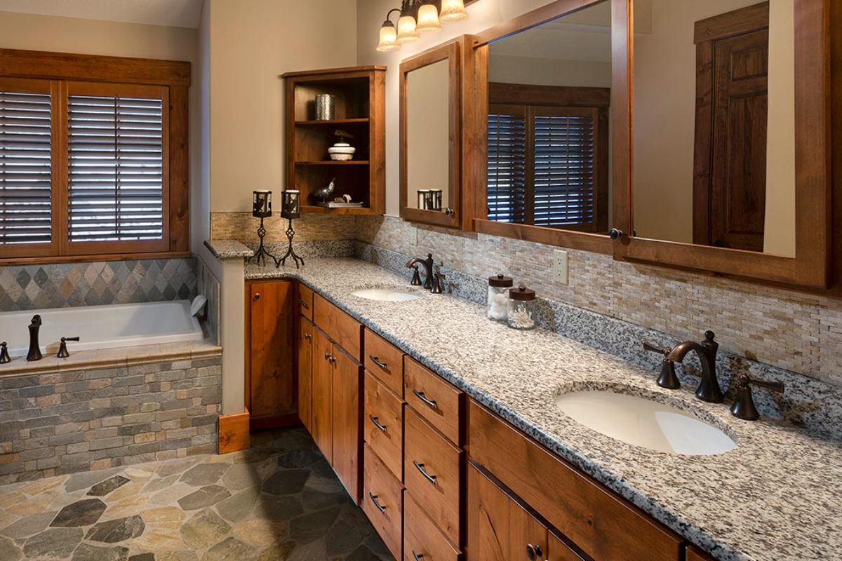 light countertops in bathroom with dark wood cabinets and mirror trimmed in dark wood above