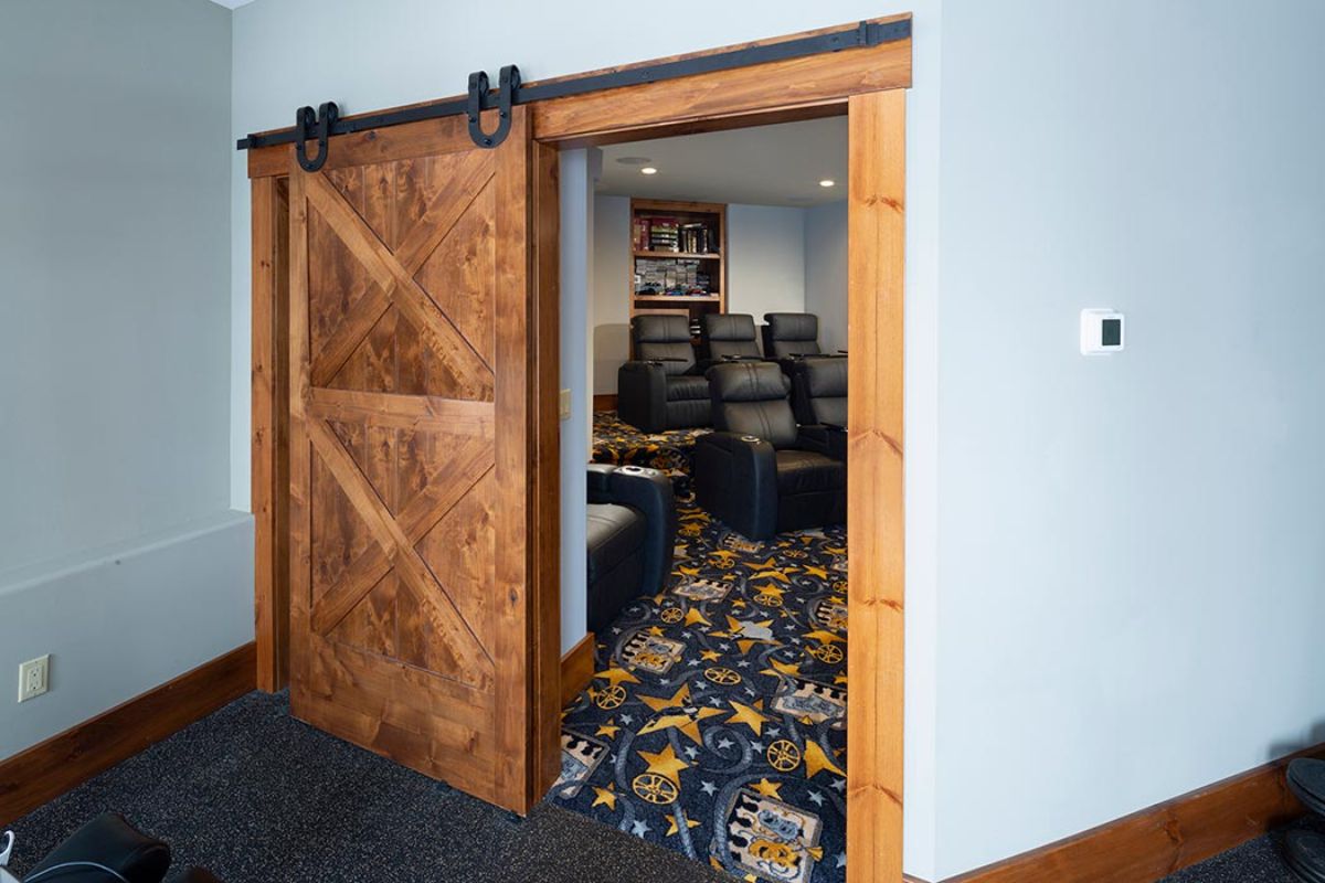barndoor style door on entry to at home theater with colorful carpet