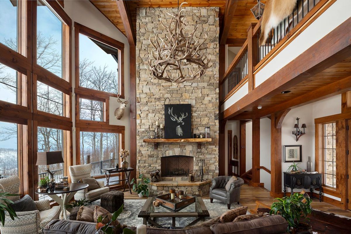 stone fireplace against far wall of log cabin with leather sofas on all sides