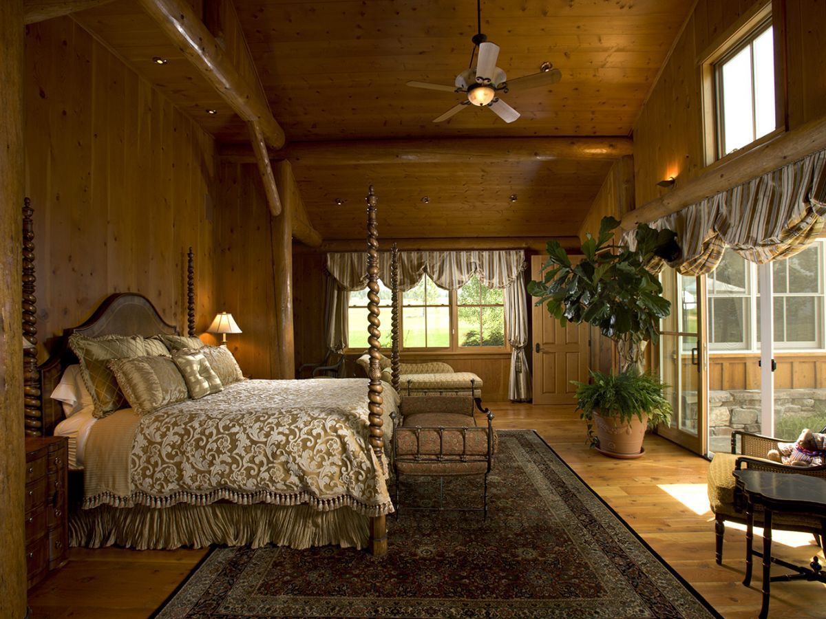 white bedding on four poster bed in large master room of log cabin