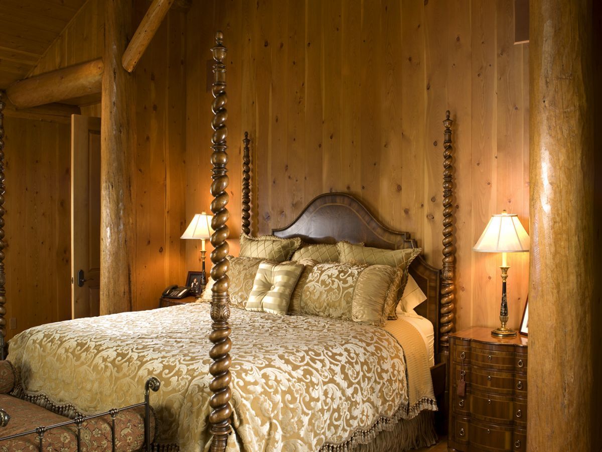 bed against log cabin wall with cream and gold bedding