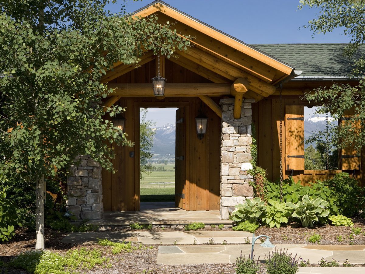 stone path leading to porch with log awning over the top on cabin