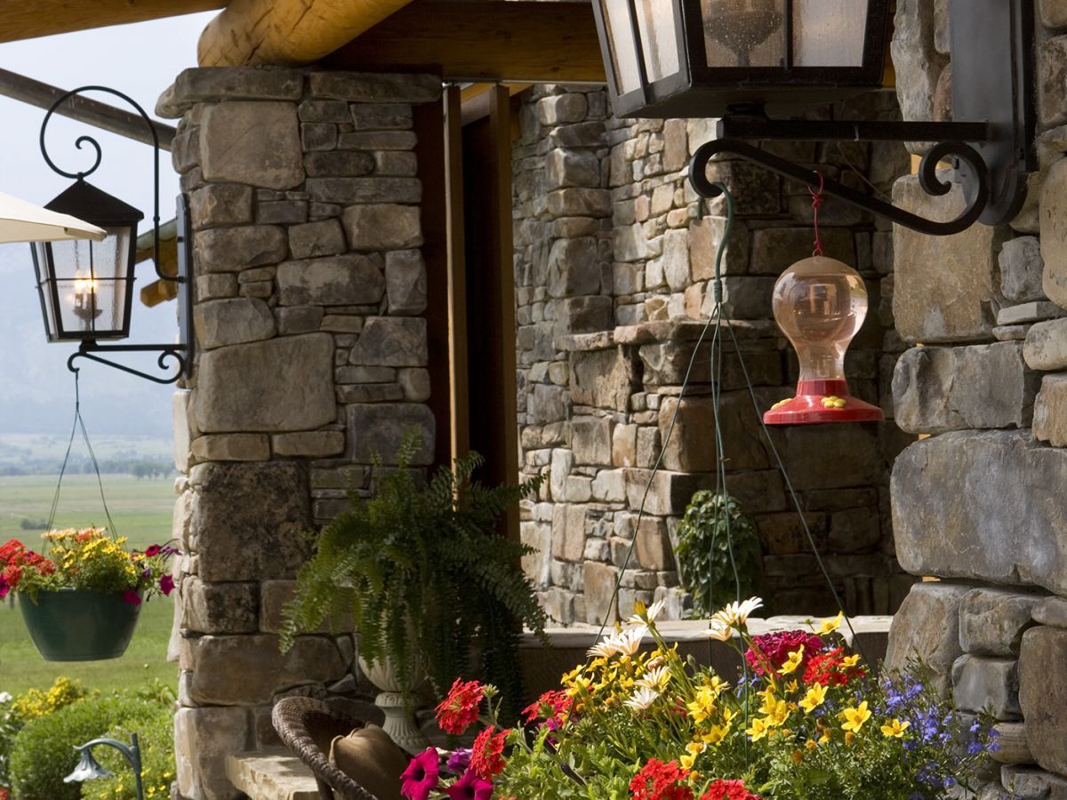 hanging basket of flowers by stone columns on front of home