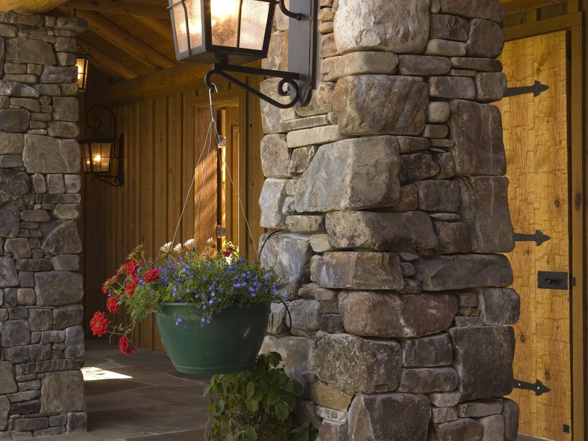 black lantern light on stone column of log cabin porch