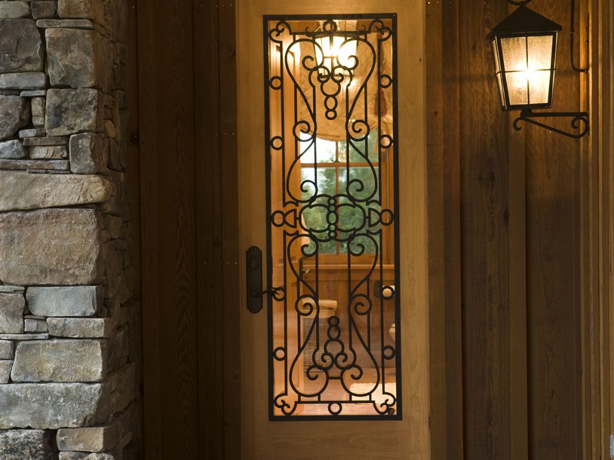 intricate wrought iron bars on glass pane front door to log cabin
