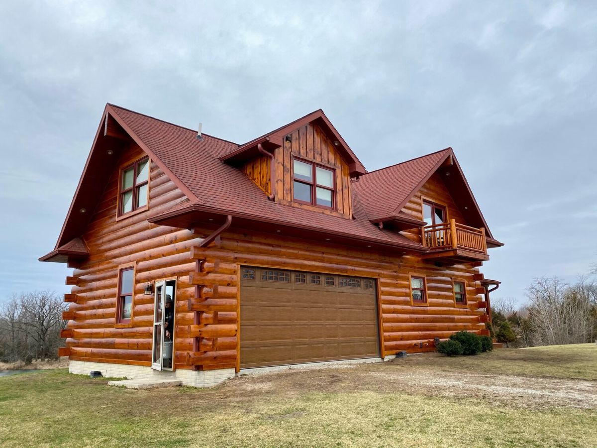 brown garage door on log cabin with dark red roof