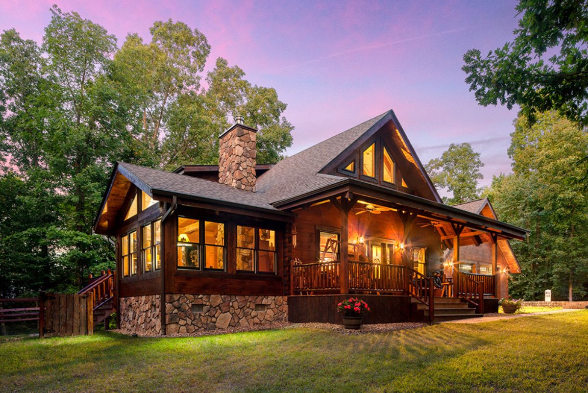 dark wood log cabin with stone foundation on left side of image