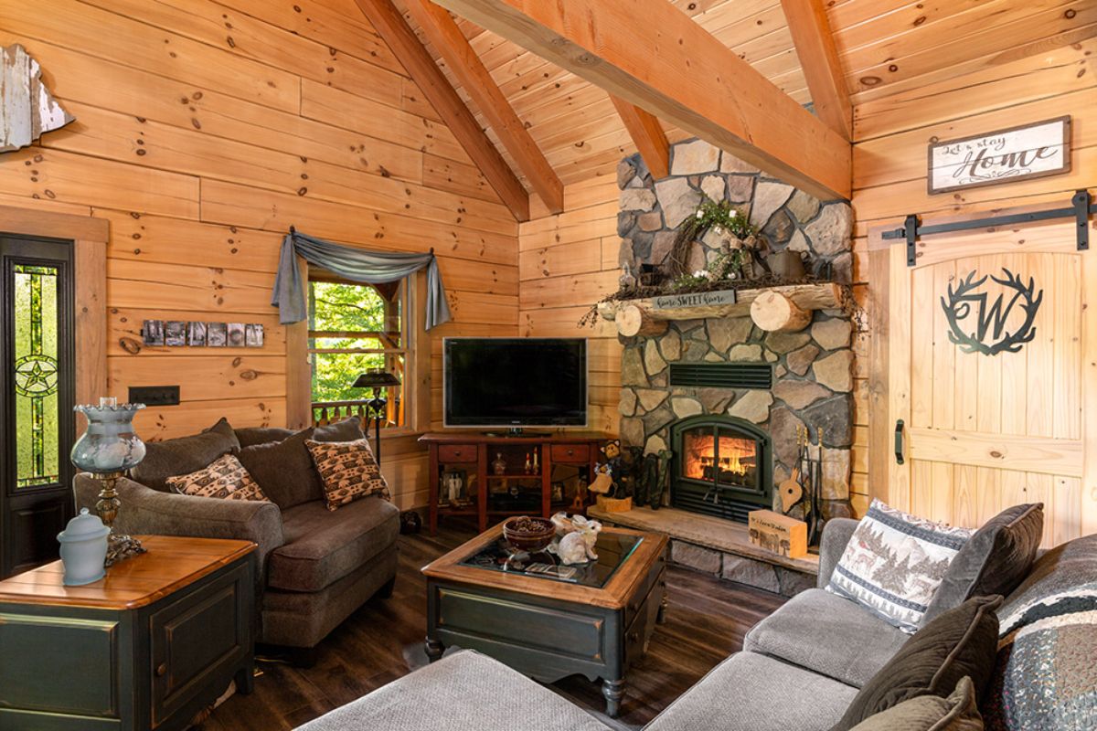 stone fireplace against right wall with television on stand in corner next to window