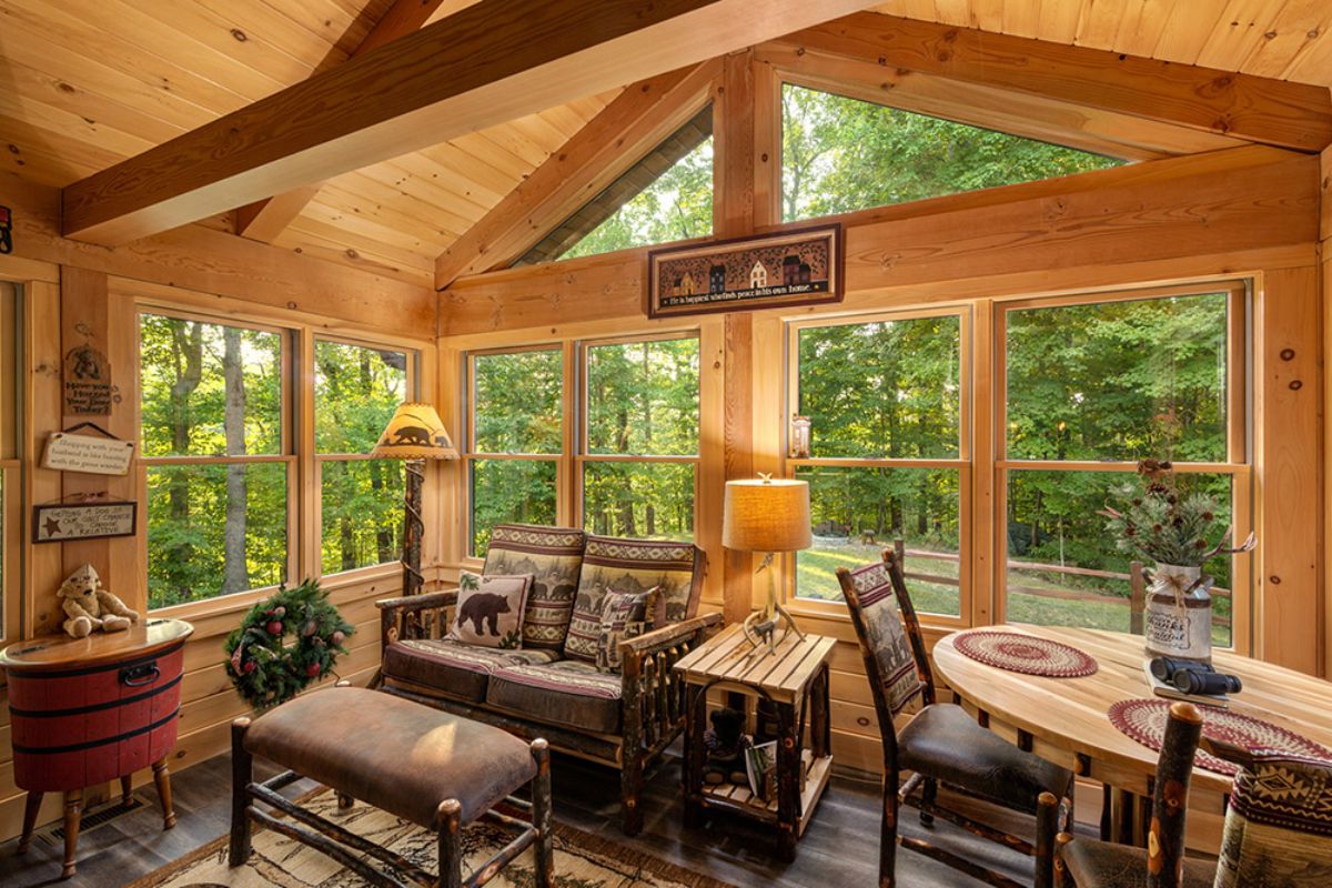 dark brown cushion on rustic brown wood chair with ottoman in front of floor to ceiling windows