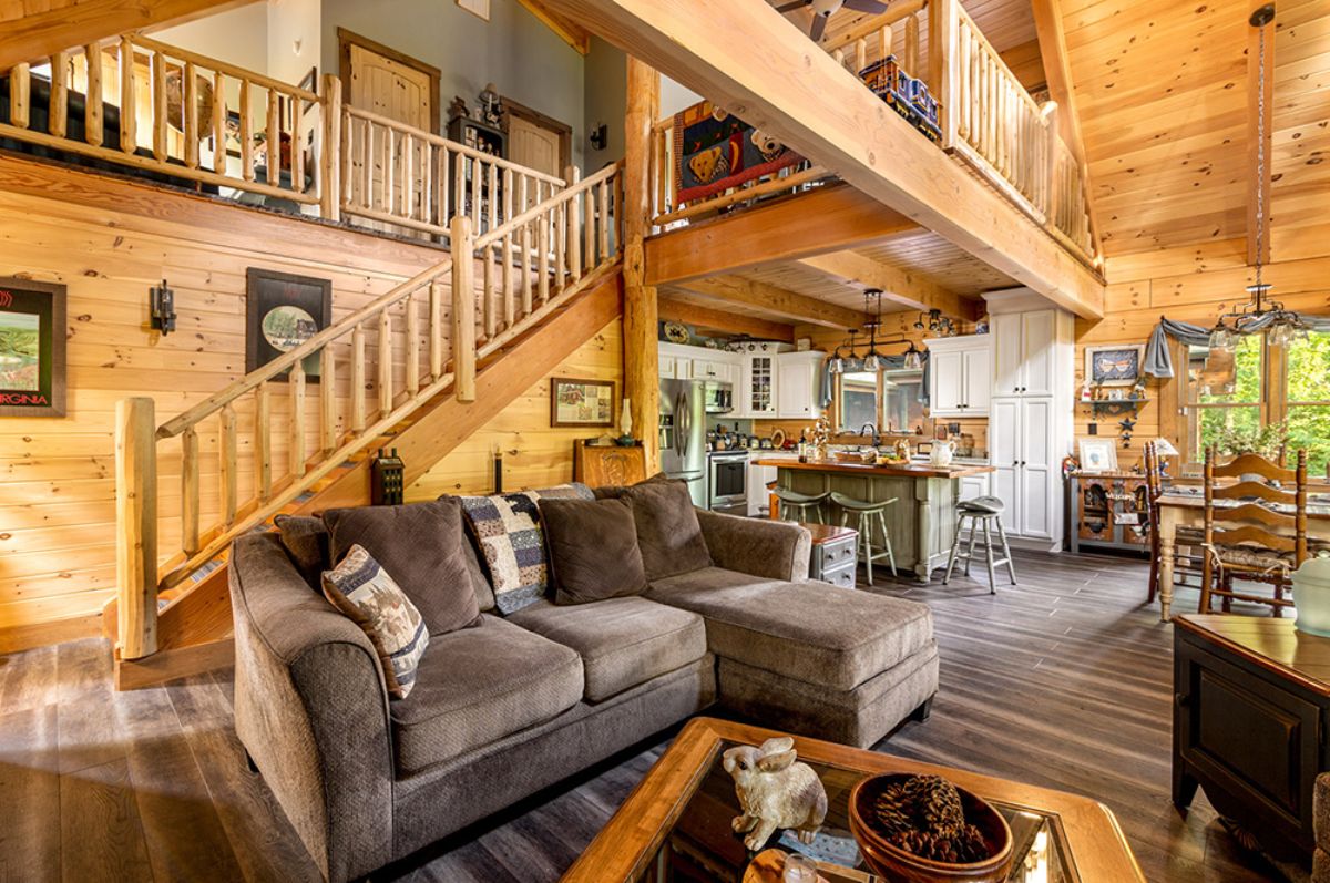 brown sofa against stairs to loft in log cabin