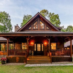 front of dark wood log cabin with covered front porch