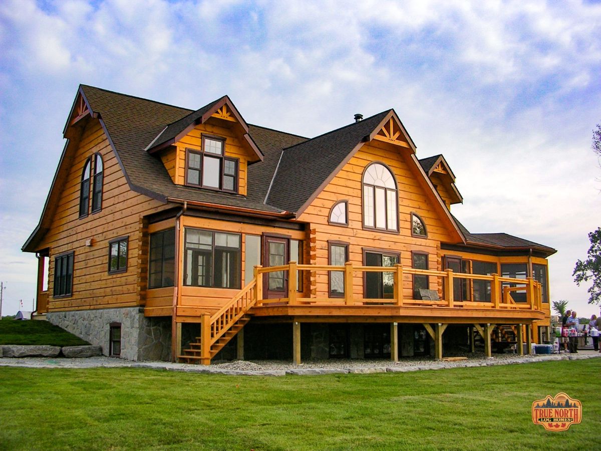 two story log cabin with deck along the back wall of the home