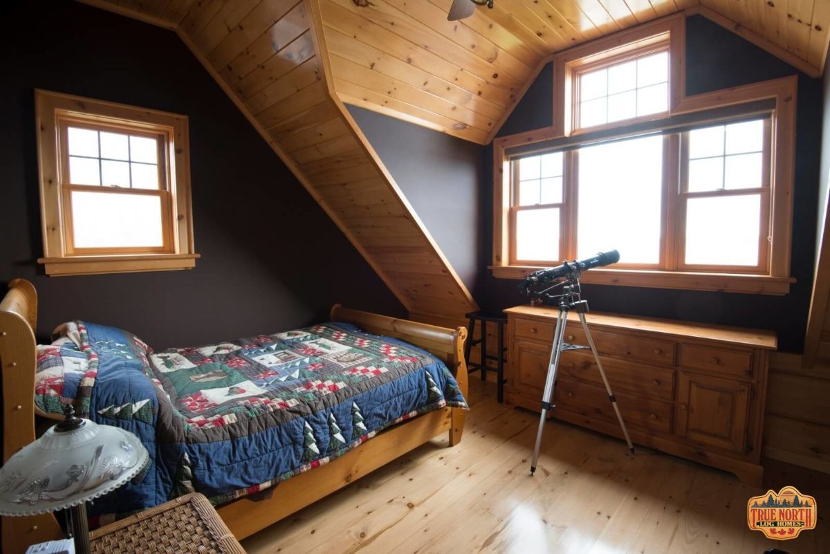 bed under eave with telescope at window in room