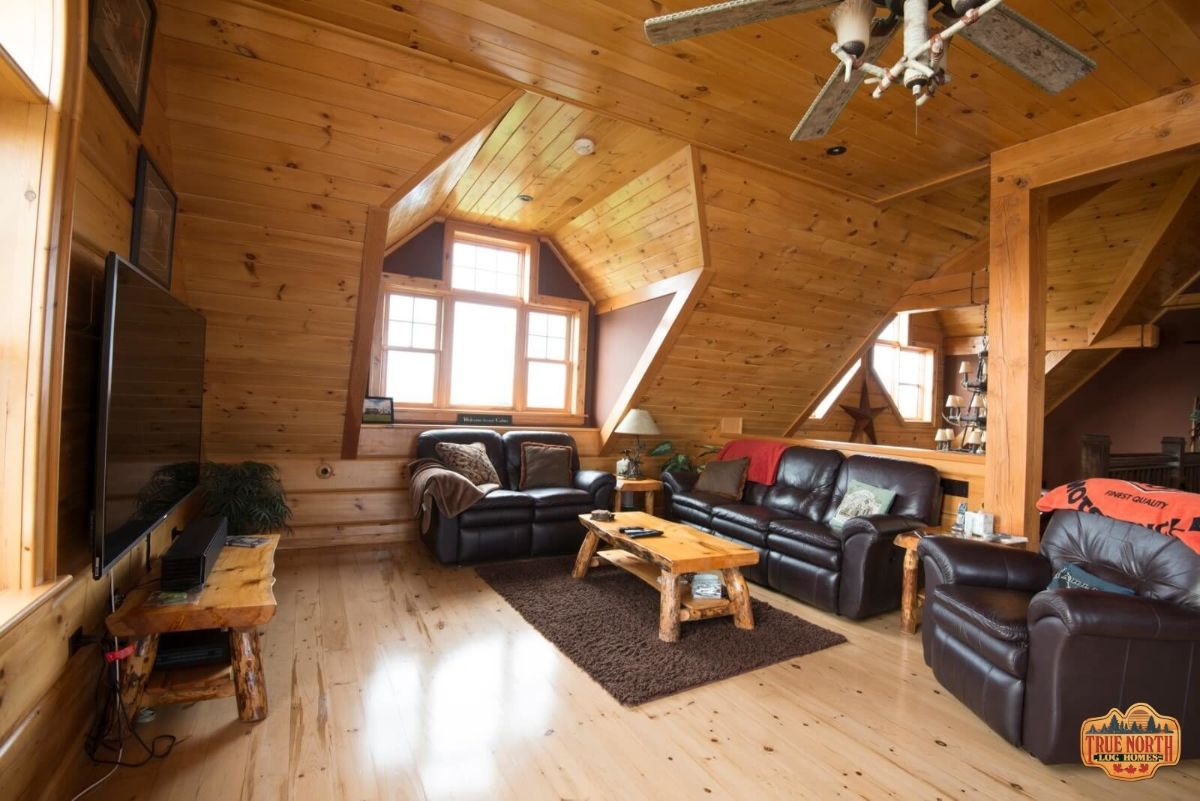 loft living space with dormer window on wall by black leather sofas and wood coffee table