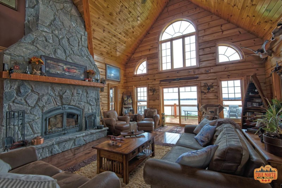 great room with wall of windows, brown sofas and stone fireplace
