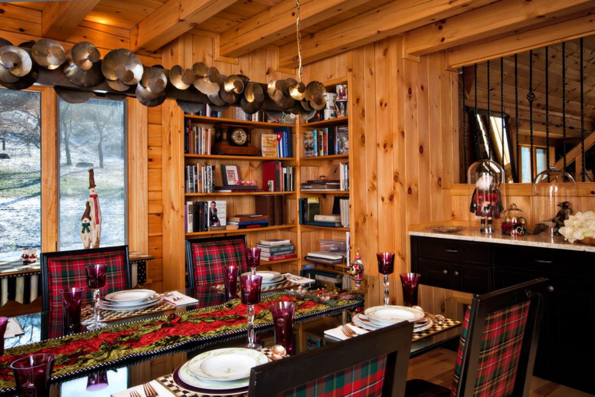 book case in back of dining room with pots and pans hanging above table