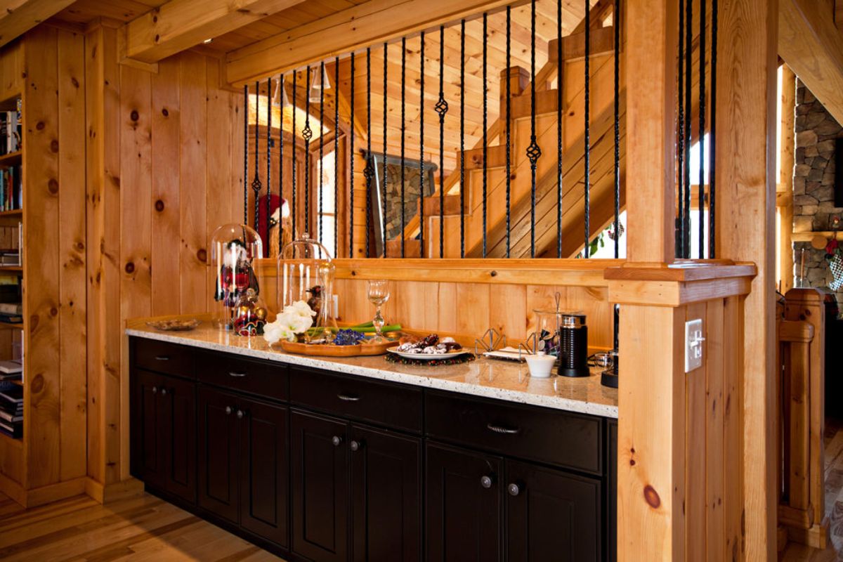 dark wood cabinets below white granite counter in kitchen with pass through looking at stairs