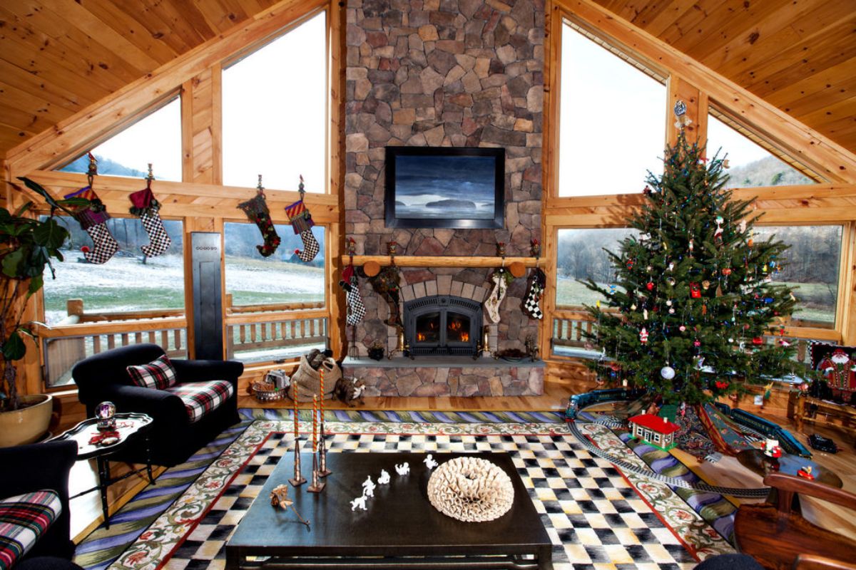 checked rug beneath dark wood table in front of stone fireplace