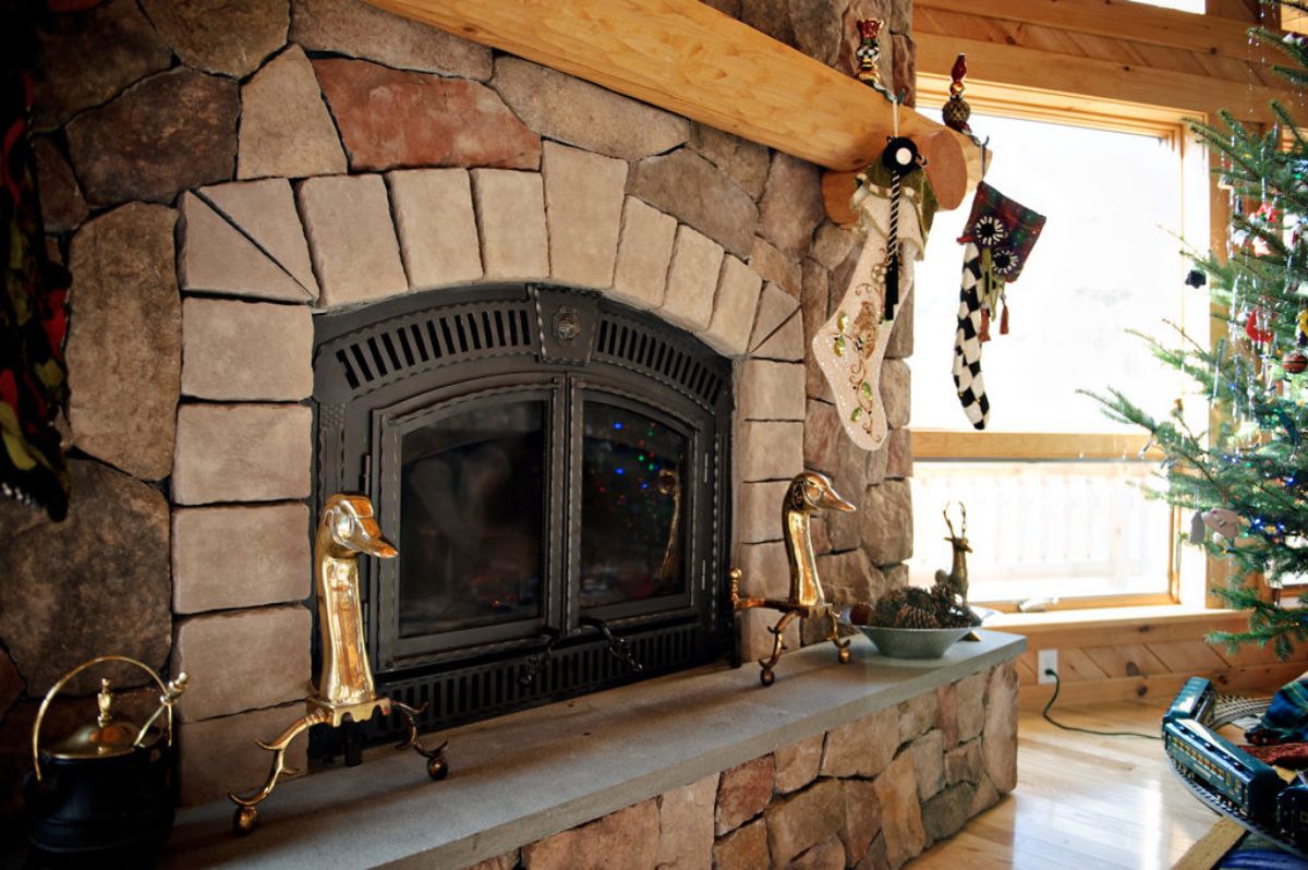 stone fireplace with brass wood holders on hearth