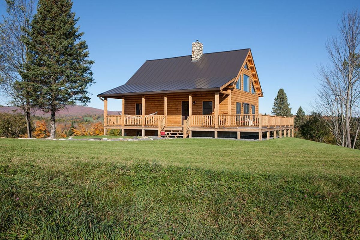 log cabin with brown shingle roof in green field