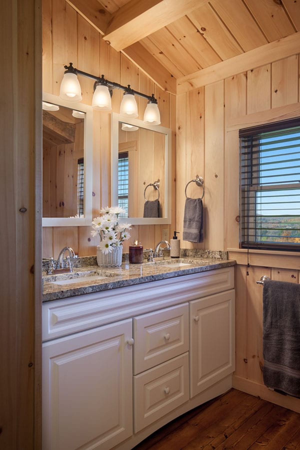 cream cabinets below brown countertop in log cabin bathroom