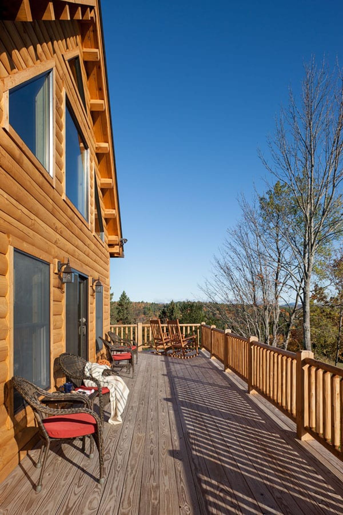 open deck off back of log cabin with lounge chairs against house