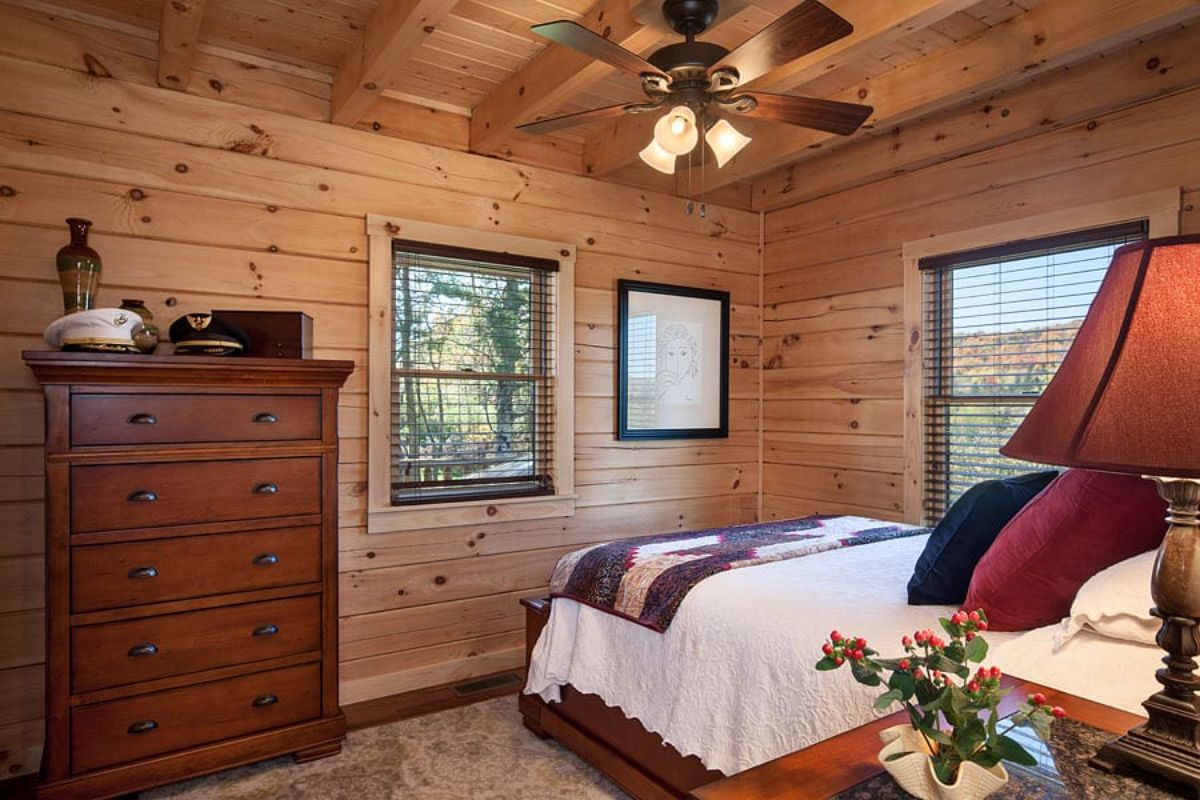 white blanket on bed in corner log cabin bedroom