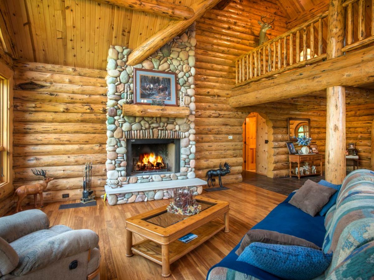stone fireplace against log wall with blue sofa in foreground
