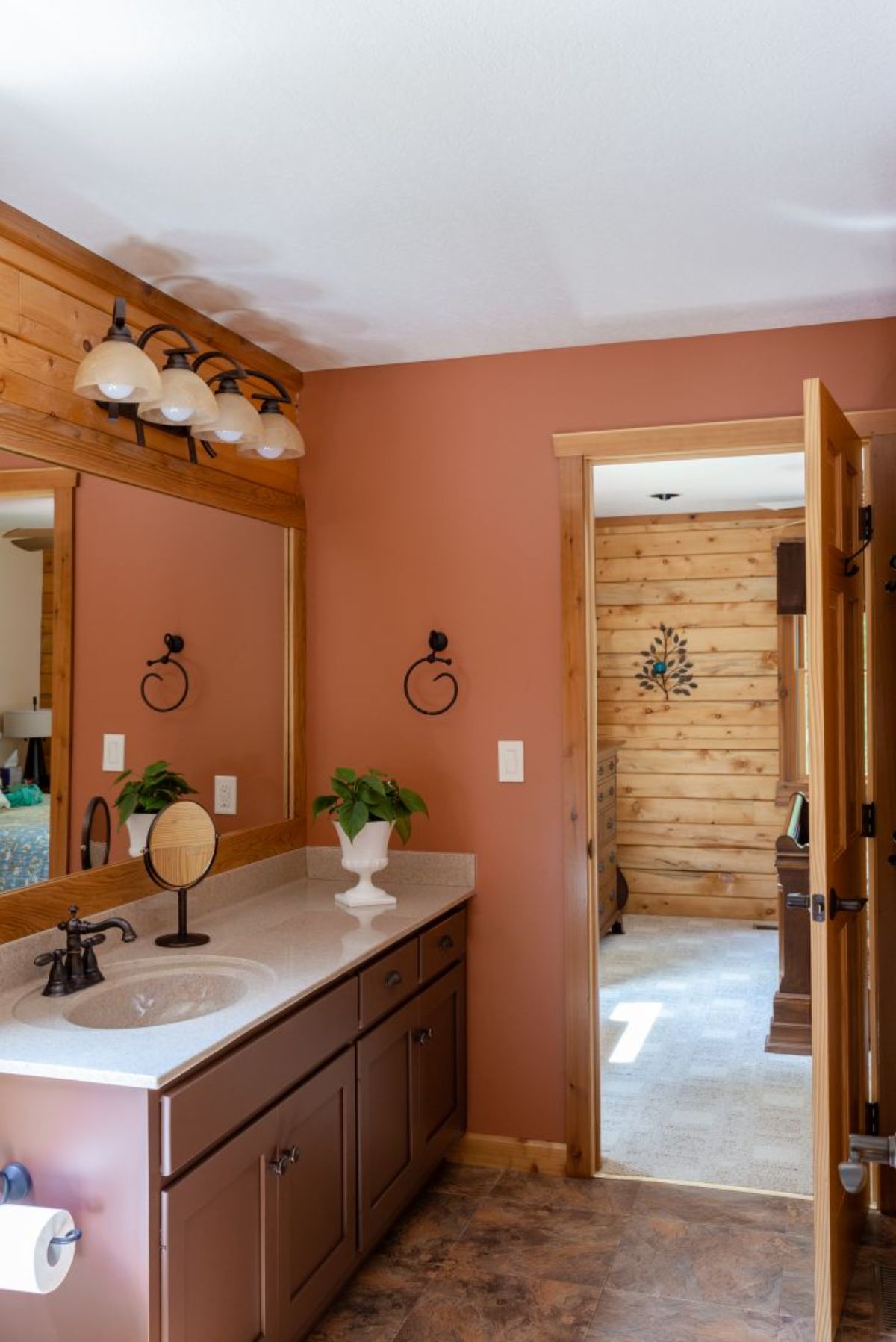 coral colored wall in bathroom with dark wood vanity and white countertops