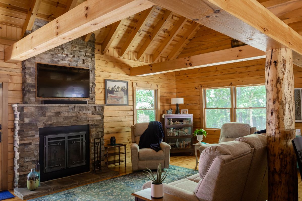 stone fireplace against log cabin wall with cream sofa in front