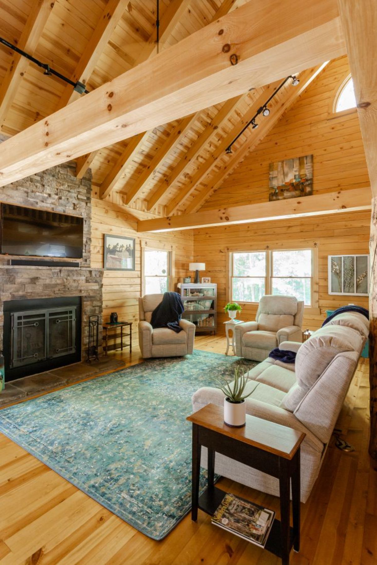 cream sofa in front of stone fireplace in log cabin with cathedral ceilings
