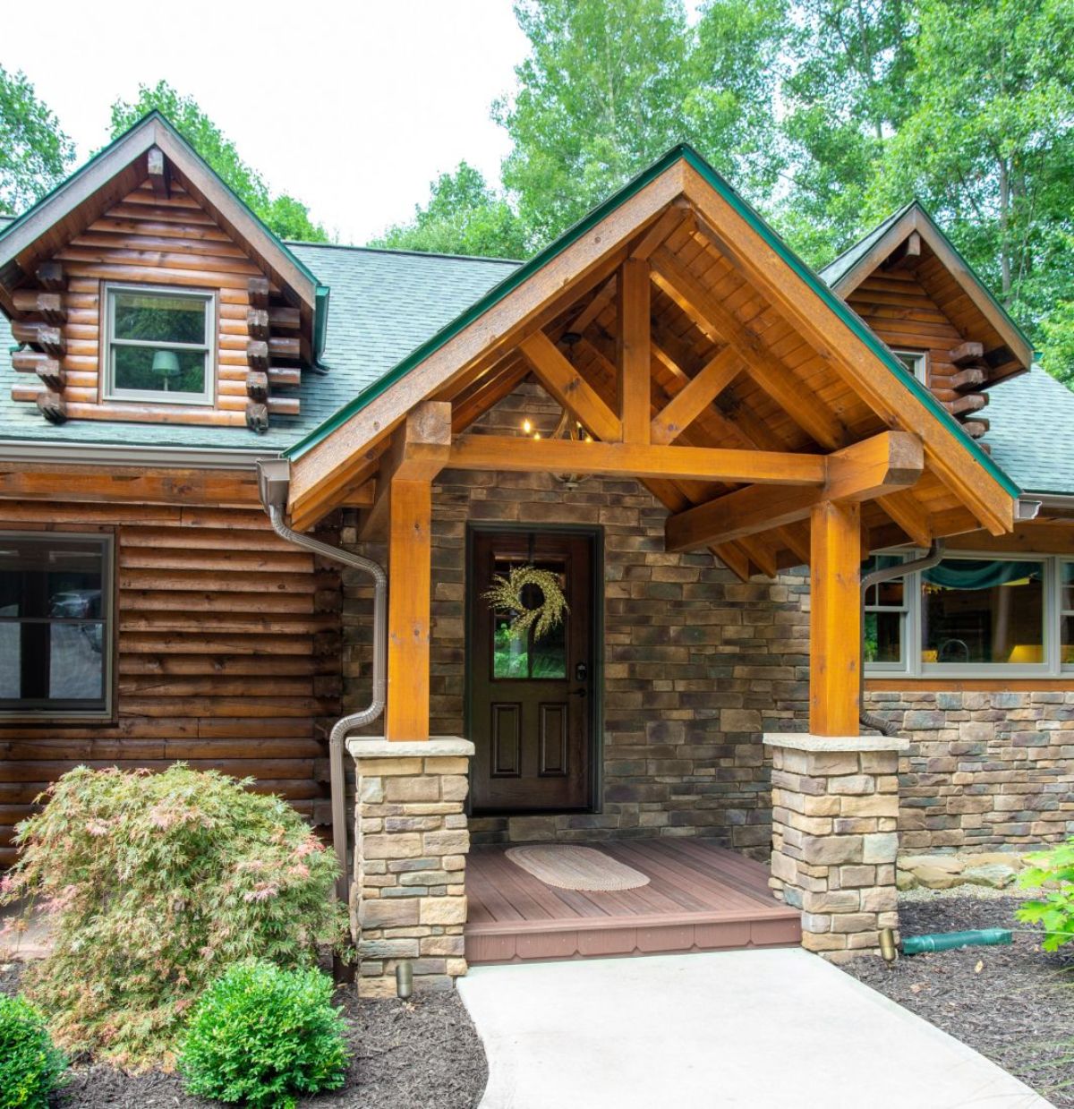 stone entry with covered porch on log cabin