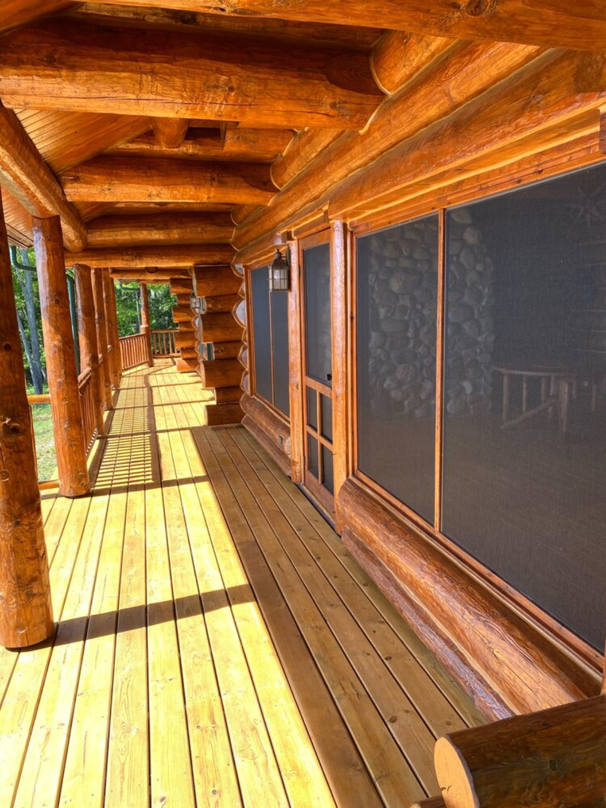 log cabin open porch with wide screens on windows and fresh stain on logs
