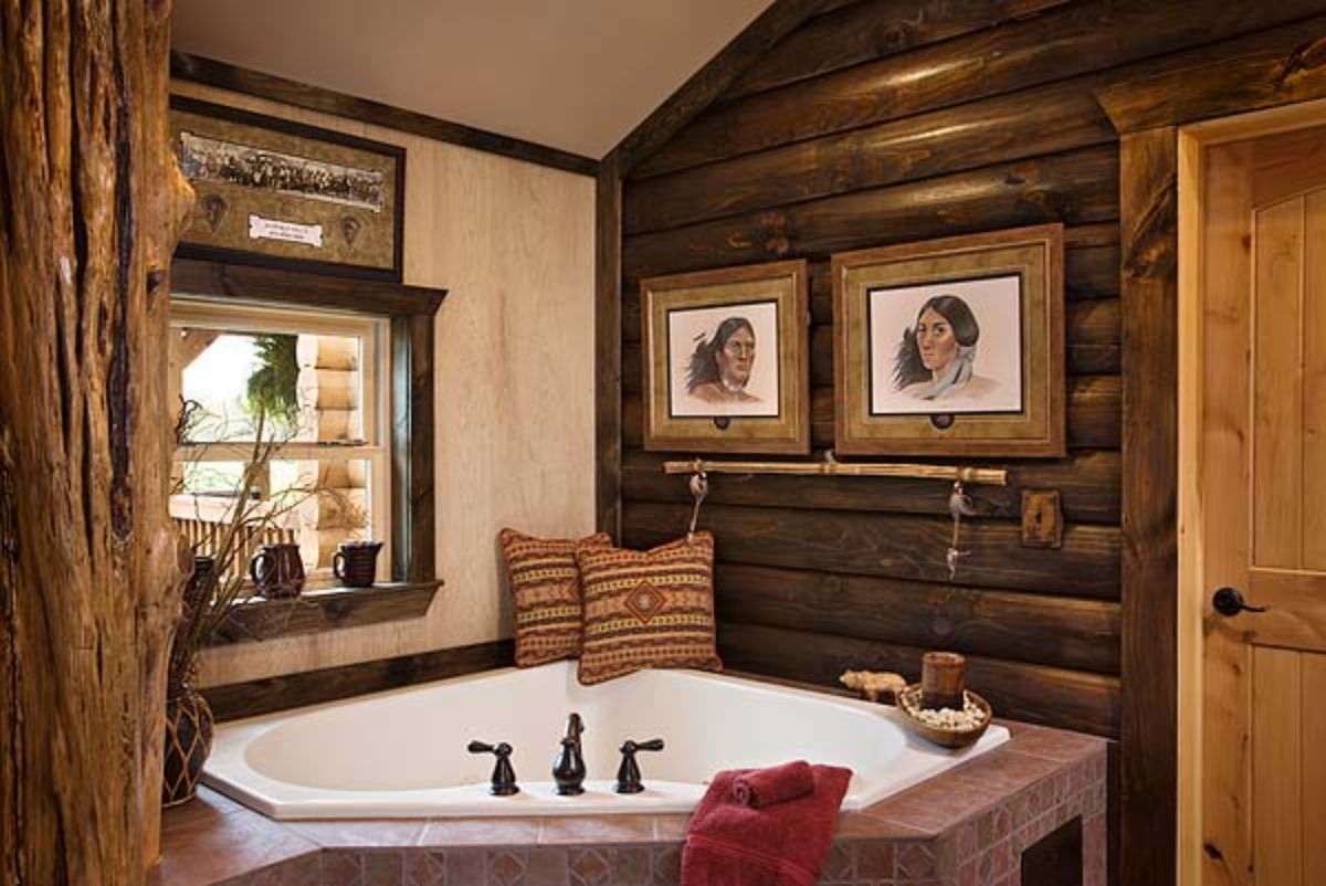 white soaking tub in back corner of log cabin bathroom with dark wood log walls
