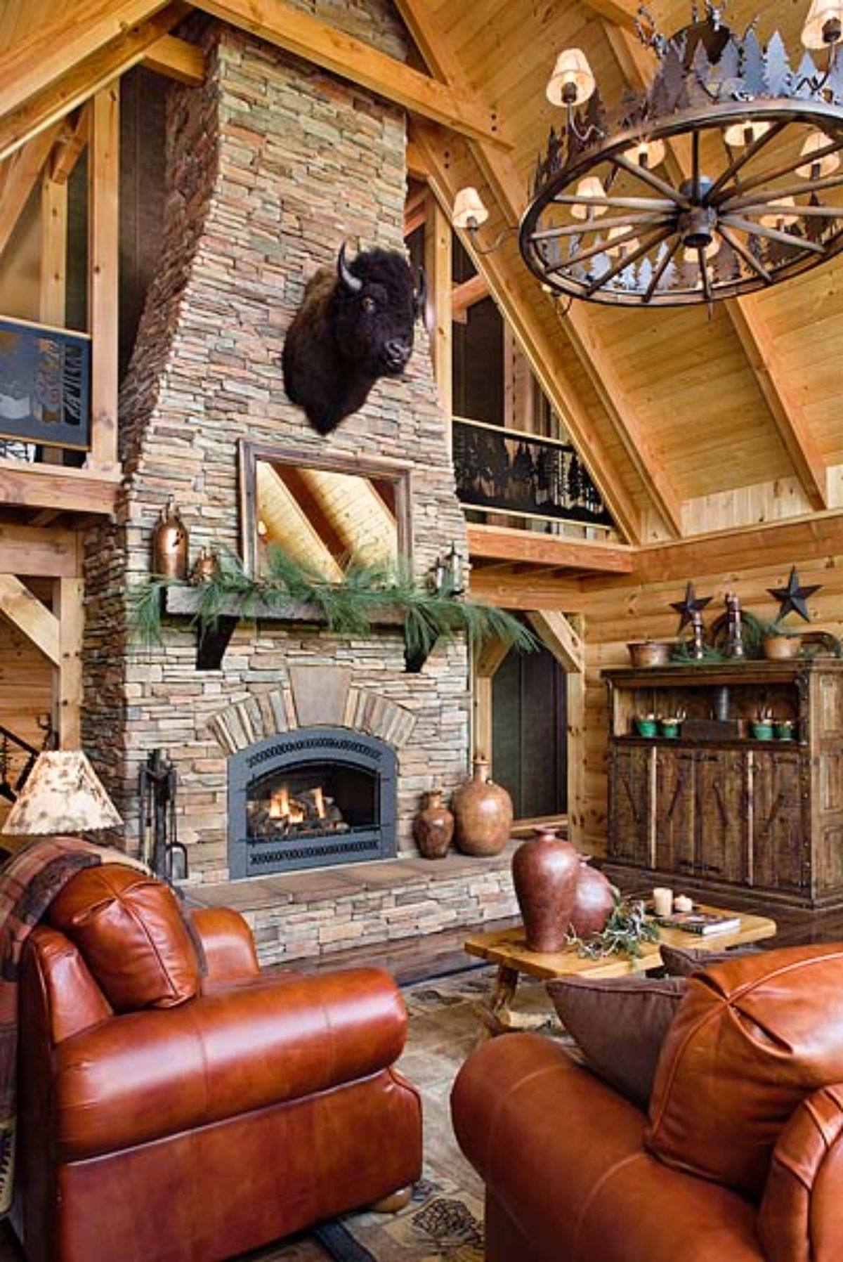 stone fireplace in living room with brown leather sofa on left and animal head mounted above mantle on fireplace