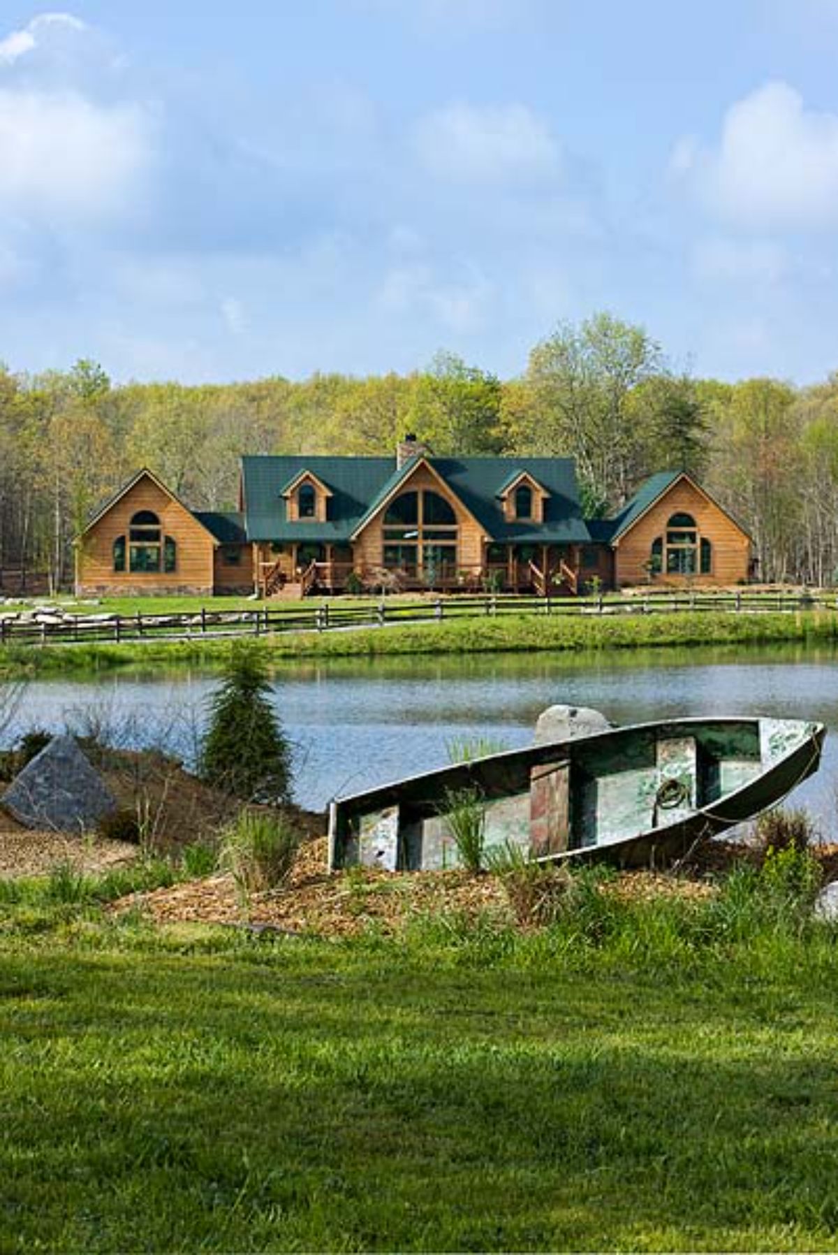 old wooden boat leaned agaisnt edge of pond behind log cabin