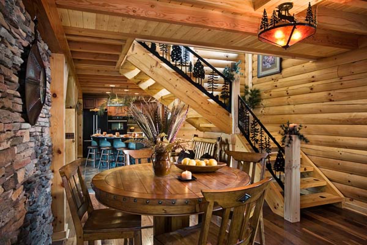 round dining table beneath loft with stairs in background with black wrought iron railings