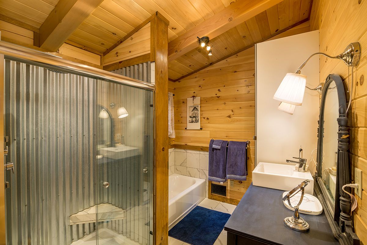 corrugated metal shower with white bathtub on the other side of wall in bathroom