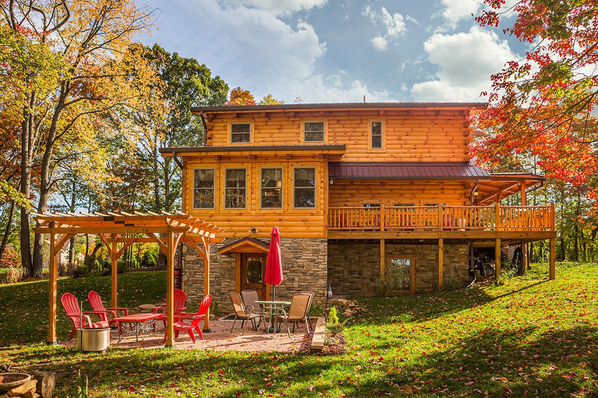 back of three level log cabin with stone foundation at walkout basement