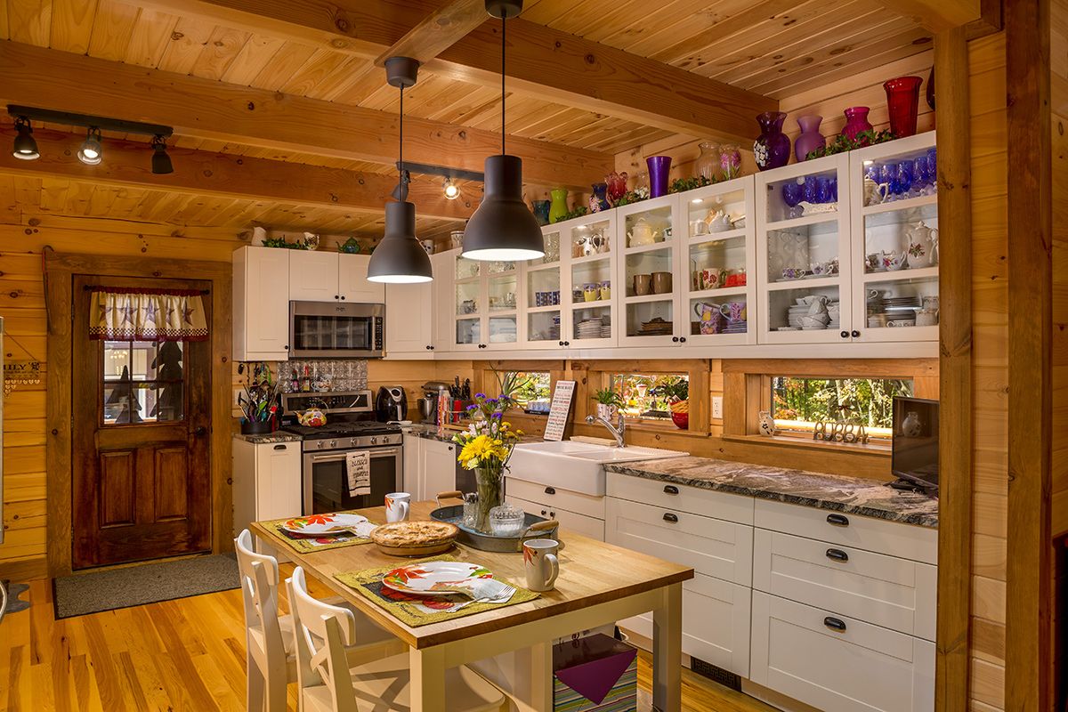 wood island next to white kitchen cabinets with upper cabinets having glass open doors