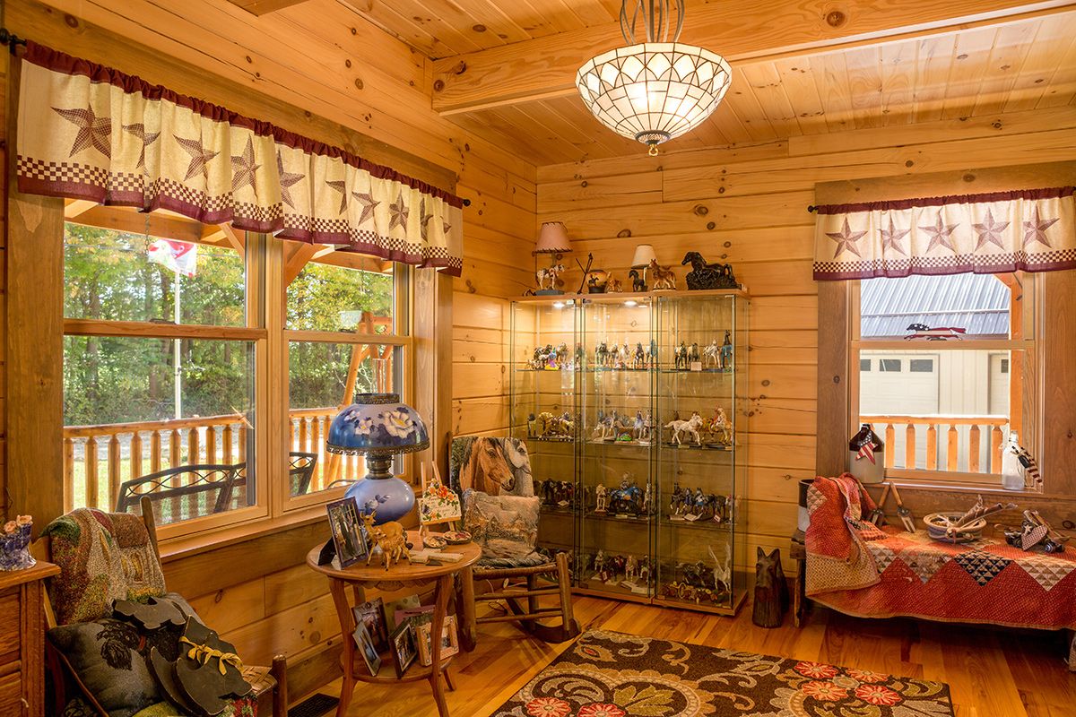 glass curio cabinet against  wall near window in log cabin