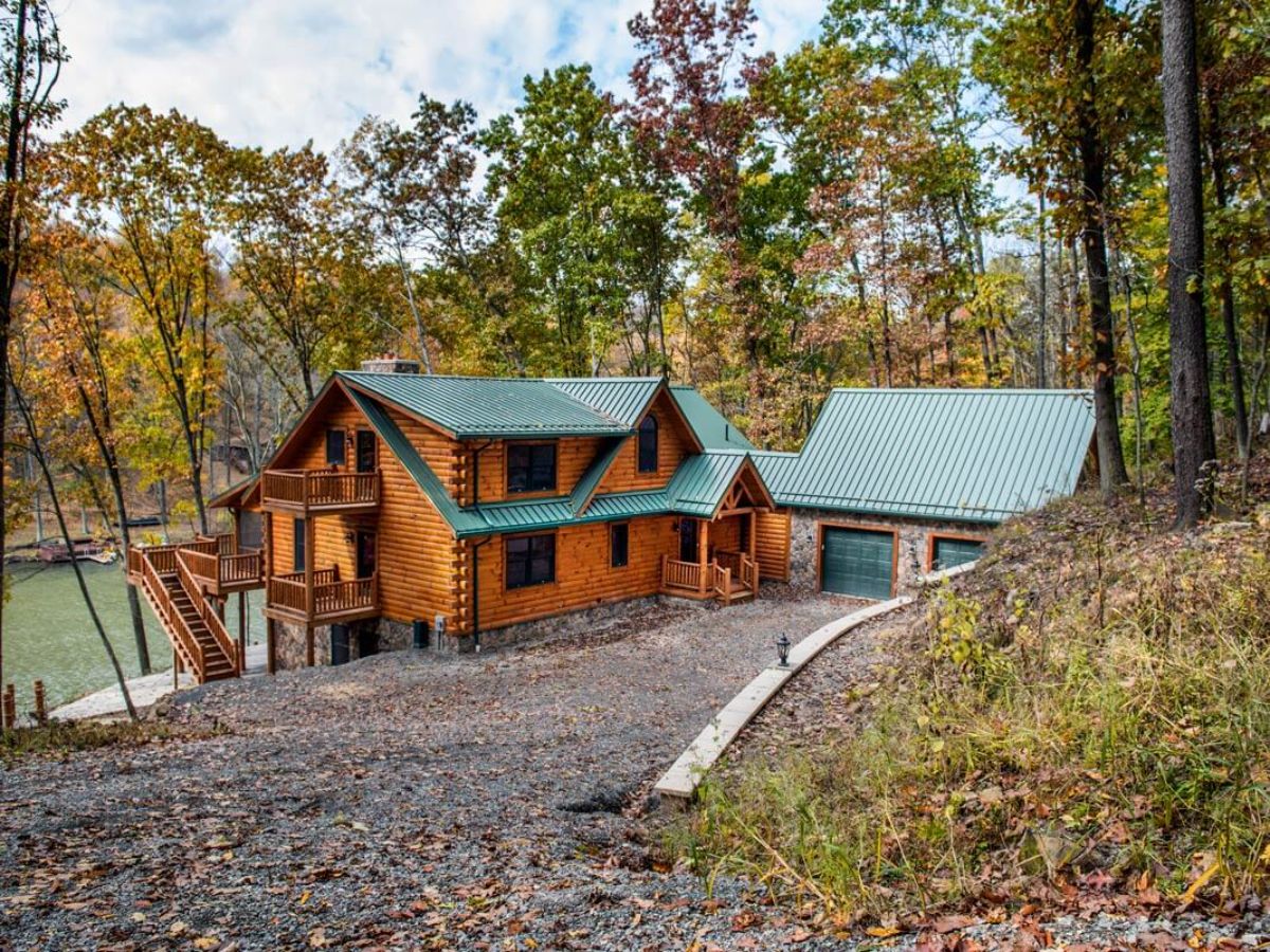 front drive of log cabin showing garage with green roof