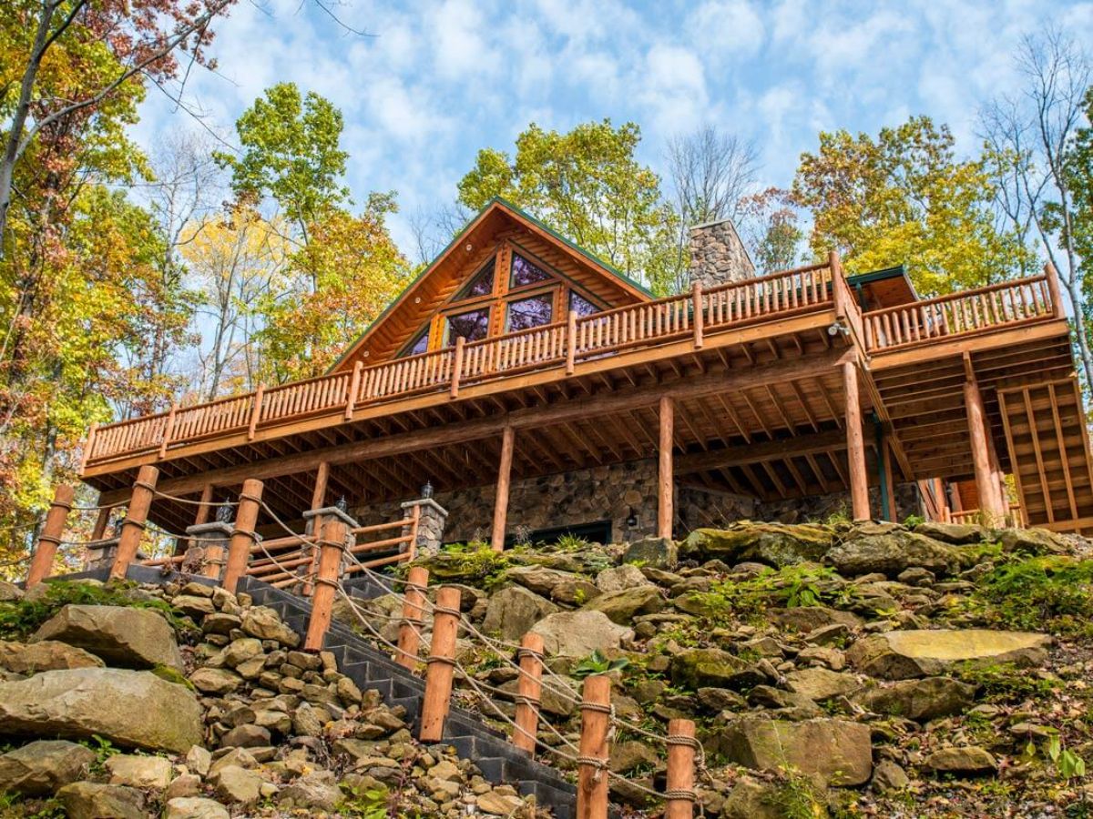 log railing on walkway leading up rock path to log cabin at top of hill