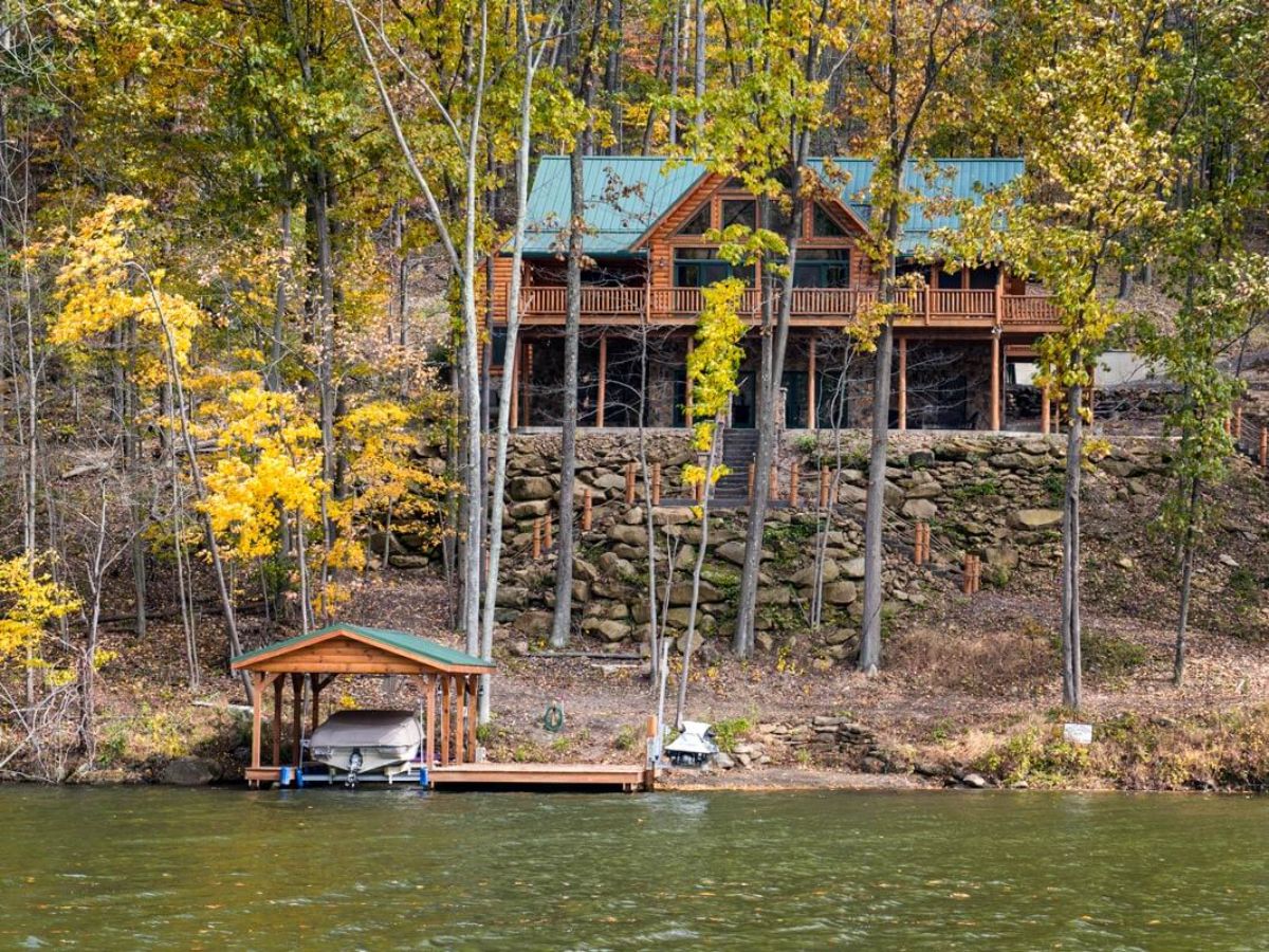 log cabin visible in trees across from lake