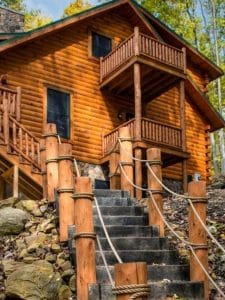 stairs up to log cabin with log railing and ropes
