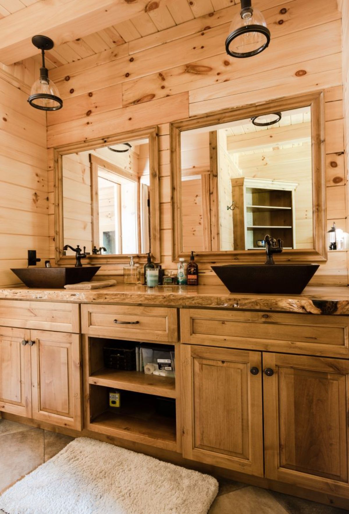light wood cabinet below copper sink in log cabin bathroom